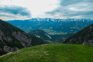 Scenic aerial view of majestic alpine landscape with snow-capped mountain ridges of Schladminger Tauern in Ramsau am Dachstein, Styria, Austria. Hiking trail through alpine greenery in Austrian Alps