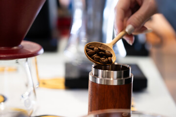 Close-up of coffee beans in a wooden spoon being poured into a wooden bottle