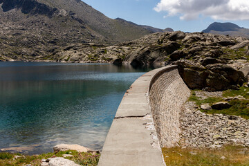 Mountain pond divided between mountains of stones and retaining wall