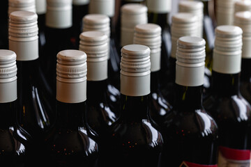 Storage of quality wine bottles with screw caps in a wine rack Close up of metal caps on dark glass wine bottles 