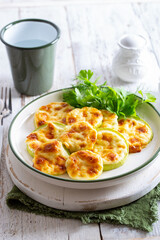 Baked zucchini with cheese, garlic on a white wooden background,selective focus.