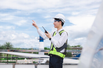 Male engineer in white hardhat standing and holding tablet working aircraft maintenance mechanics moving through hangar.