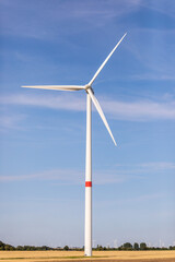 Ein Windrad auf einem Feld in der Natur mit blauem Himmel