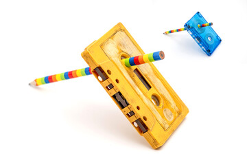 Old music magnetic cassette and wooden pencil on white background