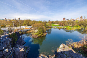 Fototapeta premium View from Belvedere Castle in Central Park Manhattan overlooking lake near rocks with skyscrapers in background. 