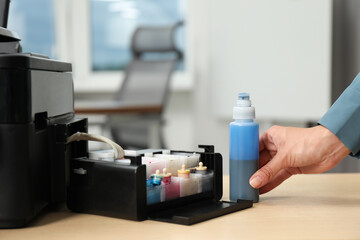 Woman refilling ink in modern printer at workplace indoors, closeup