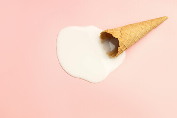 Melted ice cream and wafer cone on light pink background, top view. Space for text