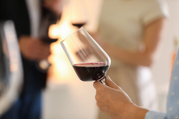 Woman with glass of red wine indoors, selective focus