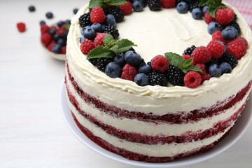 Tasty sponge cake with different berries and mint on white table, closeup