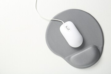 Computer mouse and mousepad with armrest on white table, top view. Space for text