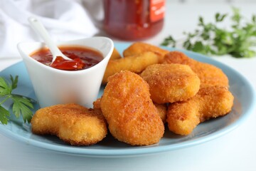 Tasty chicken nuggets with chili sauce and parsley on white table, closeup