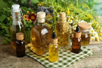 Different tinctures in bottles and medicinal herbs on wooden table
