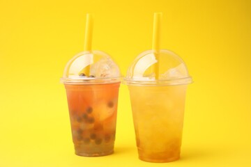 Tasty bubble tea in plastic cups on yellow background