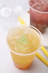 Tasty bubble tea in plastic cups and straws on light table, closeup
