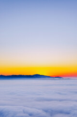 Gradient sunrise horizon and a dreamy sea of clouds