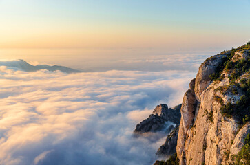 Close up of Montserrat mountain rocks with a sea of dreamy clouds and sunrise light