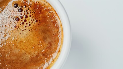Detail of crema forming on freshly brewed espresso coffee in white cup on white background