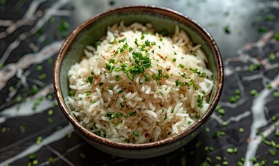 Perfectly cooked white rice in a ceramic bowl is set against a marble background, showcasing its texture and presentation.