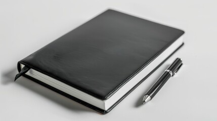 Black leather notebook and pen rest on a tidy white desk, evoking a feeling of order and sophistication