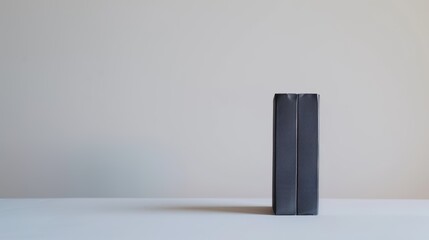 Nostalgic black vhs video cassette tape standing on a white table against a neutral background, evoking memories of a bygone era of home entertainment
