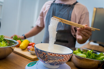 Chef at the kitchen preparing spicy glass noodle salad