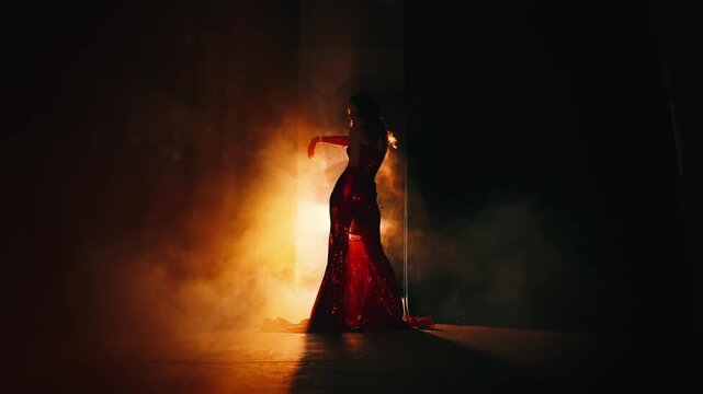 Sexy woman retro lady rear view dancing. art video glamour dark shadow silhouette girl long red shiny dress ball gown. Black room night club full smoke model posing back lit bright warm rays light 4k