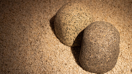 Two grey granite stones on small white gravel in a minimalist Japanese garden.