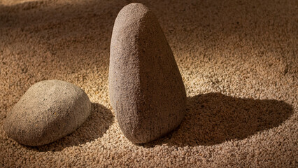 Two grey granite stones on small white gravel in a minimalist Japanese garden.