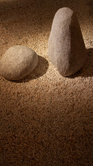 Two grey granite stones on small white gravel in a minimalist Japanese garden.