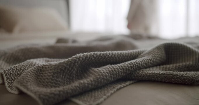 Close-up of a cozy knitted blanket draped across a bed in a warm, serene bedroom setting. The soft natural light and neutral colors create a peaceful and relaxing atmosphere. Bed With Messy Blanket