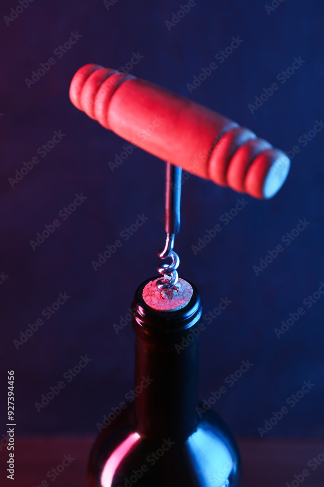 Canvas Prints Wine bottle with corkscrew in lights on dark background, closeup