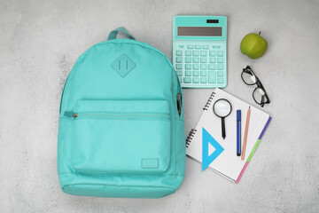Flat lay composition with backpack and different school stationery on light grey table