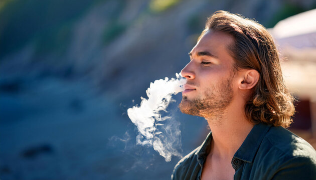 A young man vaping relaxed and releases smoke coming out