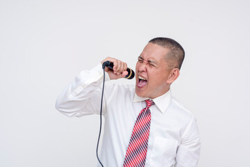 A middle aged asian man in office attire singing at the top of his lungs. Having fun, enjoying...