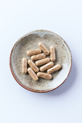 Ashwagandha (Withania somnifera) capsules. Concept for a healthy dietary supplementation. Bright paper background. Top view. Copy space.	