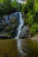 Obraz premium Waterfall in deep tropical rainforest with green rainy tree