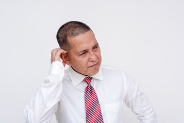 A frustrated middle aged asian manager scratches his head unsure of what to do for slumping sales. At a creative slump, running out of ideas. Isolated on a white background.