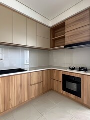 A small kitchen with light brown cabinets and wooden cupboards, a small black stove top with an empty space for an air conditioner built-in under the sink. White tiles on the floor