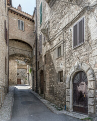 Obraz premium bridge and buttresses between old stone houses on uphill lane at medieval hilltop little town, Narni, Italy