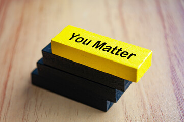 You matter text on yellow wooden block stacked on black wooden blocks. Inspirational concept