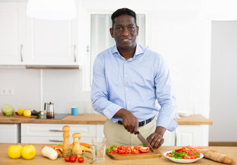 Smiling african american man eating apple in home kitchen