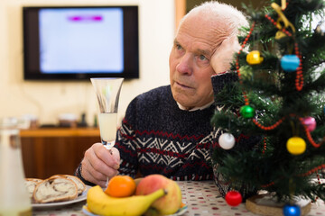 Lonely senior man sitting at home table during Christmas celebration