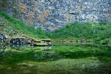 Reflection of basalt cliff and grass in Botnstjörn pond