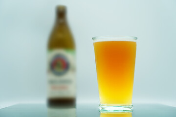 Wheat beer (orange, yellow) in a mug/glass, and in the background a beer bottle. The best German beer. Octoberfest   