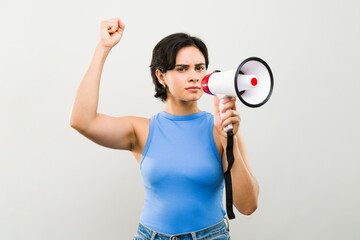 Determined female protester holds a megaphone and raises her fist, delivering a powerful message