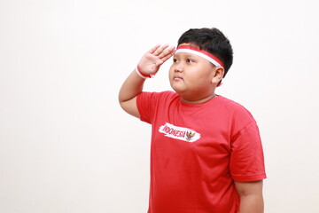 Asian boy giving salute celebrate Indonesian independence day on August 17 isolated over white...
