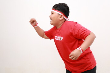 Young Asian boy with positive expression, joyful and exciting, dressed in casual cloth and red...