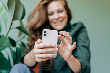 Happy smiling woman scrolls online social media on her mobile phone.