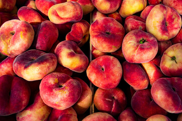 Fig peach crop. Lots of flat oval peaches at the local market as a background or food texture.