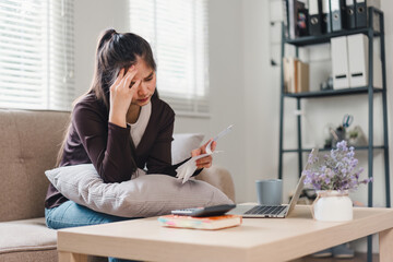 Close up of woman using calculator and holding receipts while managing finances at home.